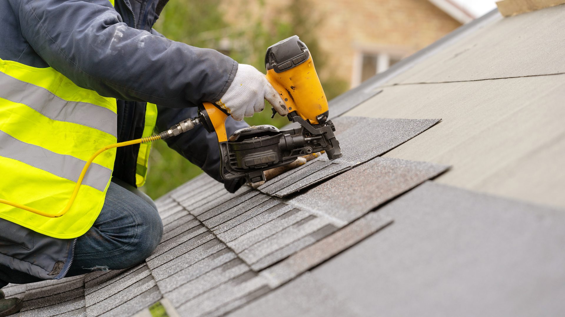 Worker Installing Bitumen Shingle On Top of the New Roof